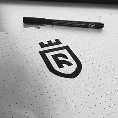 a pen sitting on top of a paper with the letter f in black and white