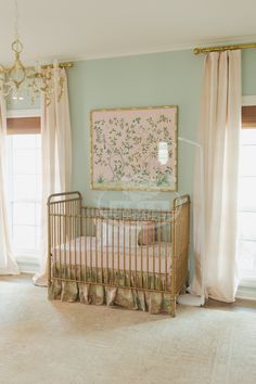 a baby's room with a crib, chandelier and window curtains