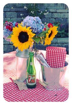 sunflowers and blue hydrangeas in a metal watering can on a picnic table