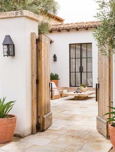 an outdoor patio with potted plants and wooden doors leading to the outside room area