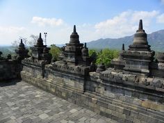 an old stone wall with many spires on it and mountains in the background,