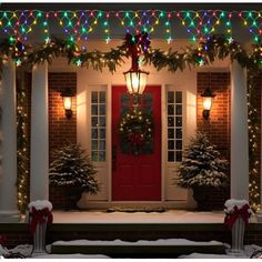 christmas lights decorate the front porch of a house with red door and wreaths on it