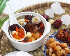 there are many different foods in the bowl on the table and one has spoons