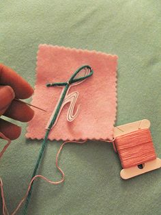 someone is knitting something on a piece of fabric with a pair of crochet hooks