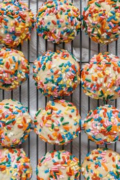 sprinkle covered donuts on a cooling rack with white frosting and multicolored sprinkles