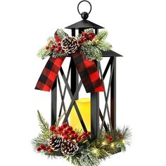 a lantern decorated with pine cones, holly and red berries is sitting on a white background