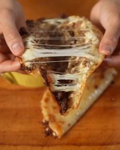 a person holding a slice of pizza with melted cheese and toppings on top of it