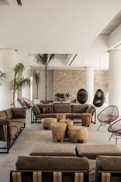 a living room filled with lots of furniture next to a stone wall and palm trees