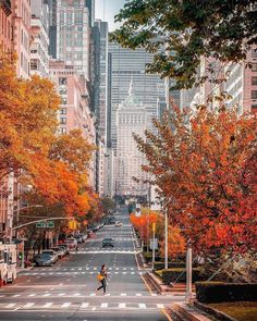 a person walking down the middle of a city street with tall buildings in the background