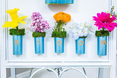 four blue vases filled with flowers sitting on top of a white shelf next to a mirror