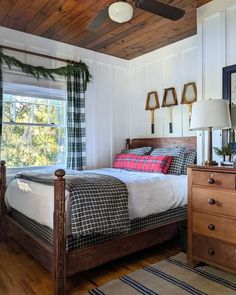 a bed room with a neatly made bed next to a window and a wooden dresser