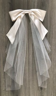 a white bow tied to a wooden door with sheer tulle on the front and back