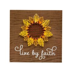 a string art sunflower with the words live by faith written in white on a brown background