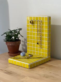 a small yellow box sitting on top of a wooden table next to a potted plant