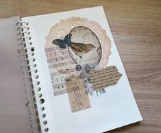 an open notebook with paper art on the pages and a bird sitting on top of it