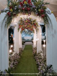 an archway decorated with flowers and greenery for a wedding or reception area at night