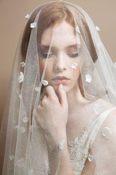 a woman wearing a veil and holding her hand to her face with flowers on it