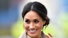 the woman is smiling and making a peace sign with her hand as she stands in front of a blurry background