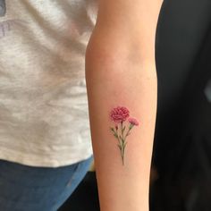 a person with a tattoo on their arm holding a flower in one hand and two pink flowers in the other