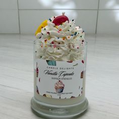 a cupcake with white frosting and sprinkles in a glass container