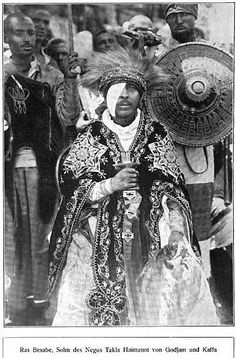 an old black and white photo of a man in native clothing with other people behind him