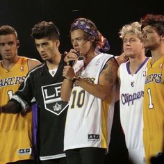 the young men are standing together on stage with microphones in their hands and one is wearing a lakers jersey