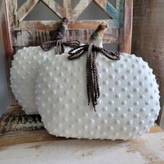 two white ceramic pumpkins sitting on top of a wooden chair