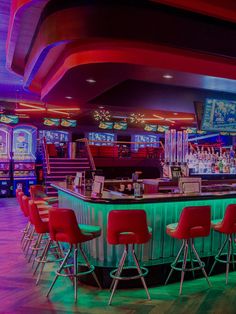 a brightly lit bar with red and green chairs