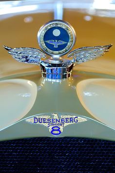 the hood ornament on an old model car is blue and white with silver wings