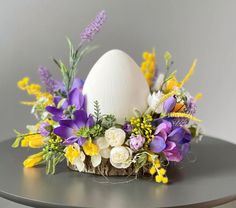 an egg sitting on top of a basket filled with flowers