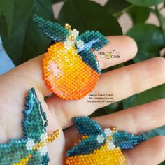 two pieces of beaded fruit are sitting on someone's hand