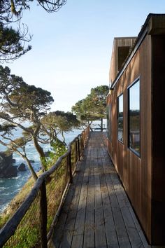 there is a wooden walkway leading to the beach and trees on the other side of the house