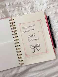 an open notebook with writing on it next to a pink pen and white paper sheet