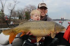 a man holding a large fish next to a little boy