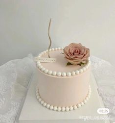 a pink cake with a single rose on top