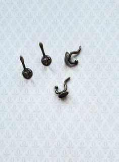 three pairs of metal hooks on a white surface with floral designs in the back ground