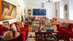 a living room filled with red couches and chairs next to a painting on the wall