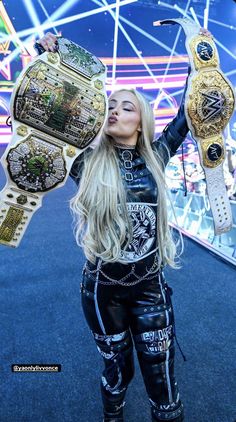 the woman is holding up her two wwe championship belts and posing in front of a ferris wheel