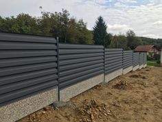 a steel fence is shown in front of some dirt and trees on the other side