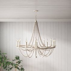 a chandelier hanging from the ceiling in a room with white walls and wood flooring