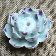 a blue and white flower sitting on top of a brown cloth covered table next to a button