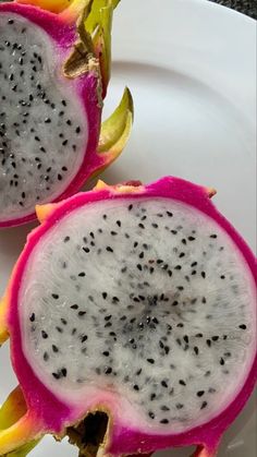 two dragon fruit halves cut in half on a white plate with black speckles