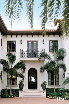 a large white house with palm trees in front