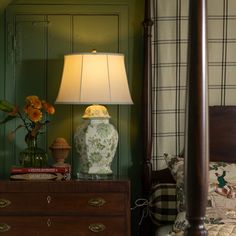 a bedroom with green walls and a white lamp on the nightstand next to a bed