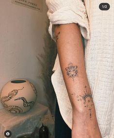 a woman's arm with tattoos on it next to a vase and other items