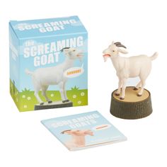 a toy goat standing on top of a wooden stump next to a box and book