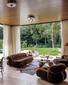 a living room filled with furniture next to a large window covered in grass and palm trees