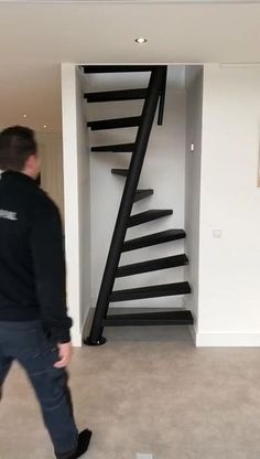 a man is walking in front of a spiral stair case that has been painted black