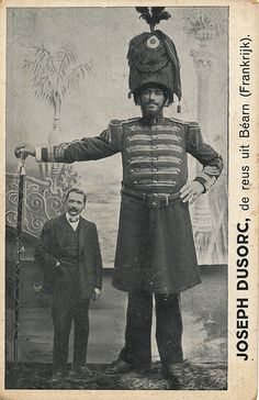 an old black and white photo of a man in uniform standing next to another man