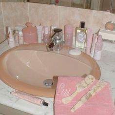 a bathroom sink with pink towels and personal care items